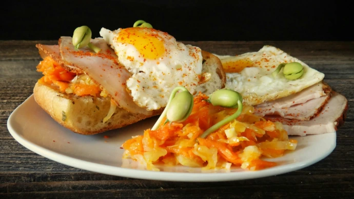 Sandwich with fried egg, bacon, and vegetables
